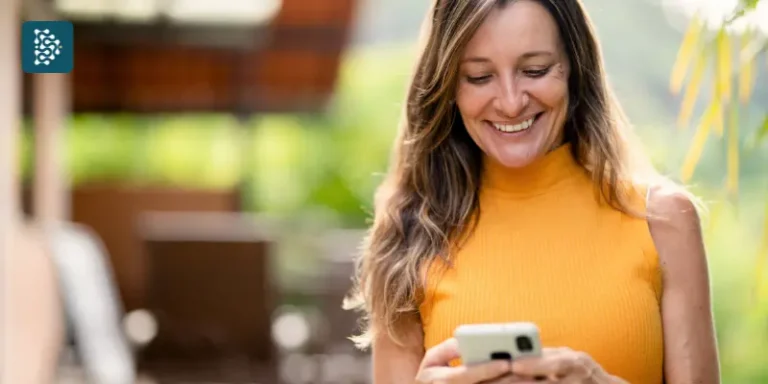 mulher loira vestindo camiseta amarela usa celular para fazer agendamento de consulta por meio de sistema de automação para clínicas
