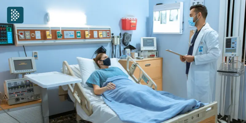 Médico conversando beira de leito com uma paciente internada