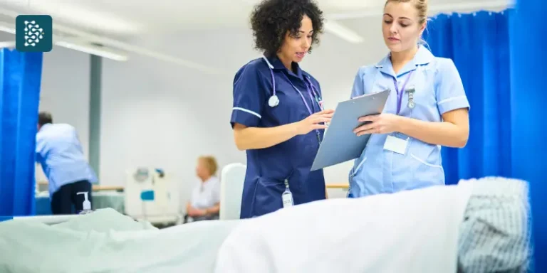 Enfermeira e Técnica de Enfermagem ao lado de um leito hospitalar