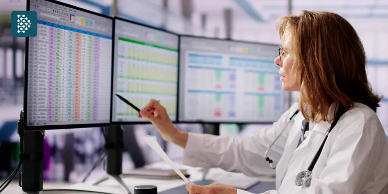 Médica analisando gráficos financeiros no computador, representando a automação de tarefas e o controle financeiro hospitalar com o sistema Datasigh Web.