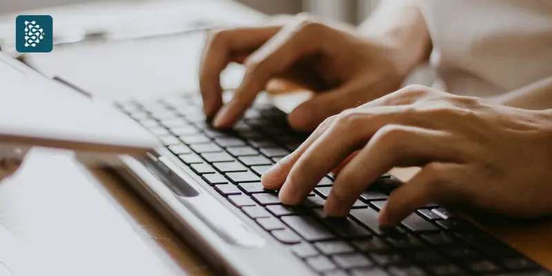 Mãos digitando em teclado para atendimento online em sistema hospitalar.