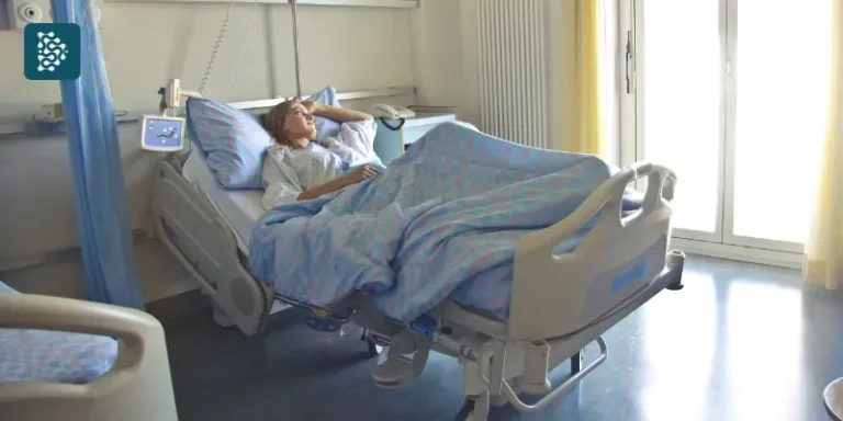 Mulher repousa em um leito de hospital-dia, em ambiente acolhedor e bem iluminado.