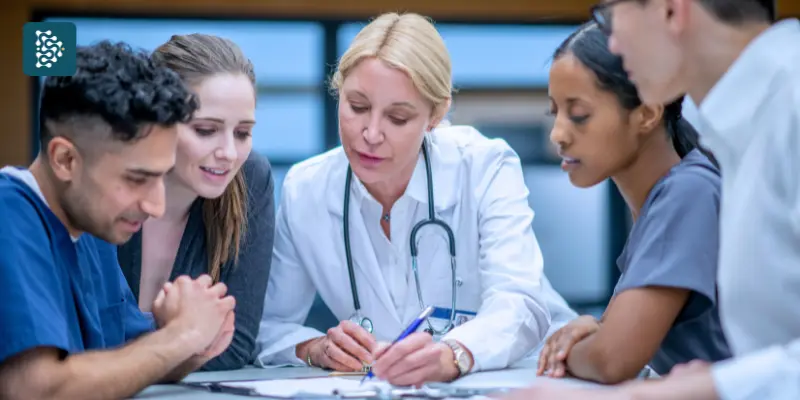 Reunião de equipe clínica em hospital com médico e enfermeiros discutindo prontuário de paciente
