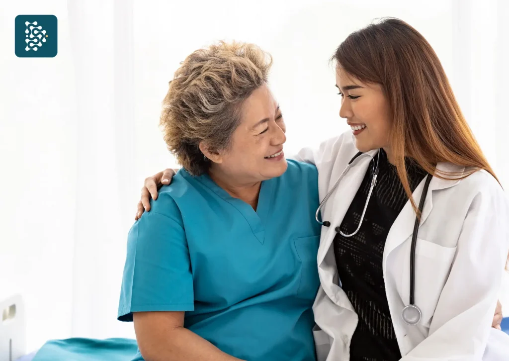 Jovem médica abraçando idosa em consultório