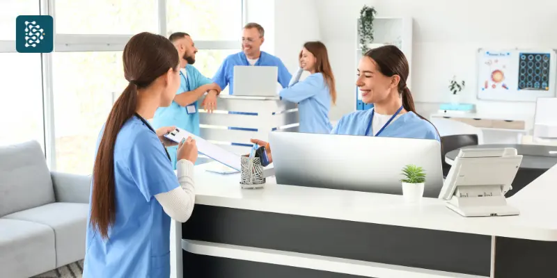 Funcionários da recepção de clínica sorrindo, ambiente de trabalho saudável com uso do sistema de gestão Datasigh.