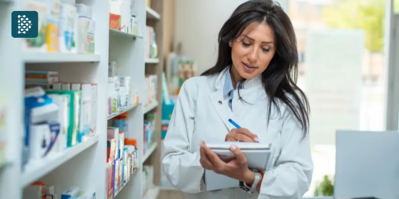 Gestão de estoque de medicamentos em clínica, com farmacêutica de jaleco branco fazendo anotações em estoque de remédios e insumos hospitalares, com apoio do sistema Datasigh.