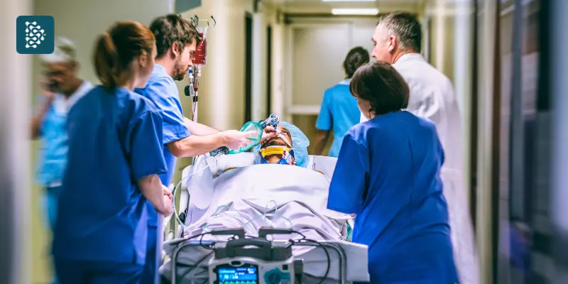 Hospital lotado com recepção cheia e enfermeiros correndo com cama e paciente, cenário que reforça a importância da gestão de hospitais com o sistema Datasigh.