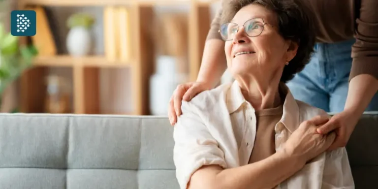 Idosa sentada no sofá recebendo abraço de conforto