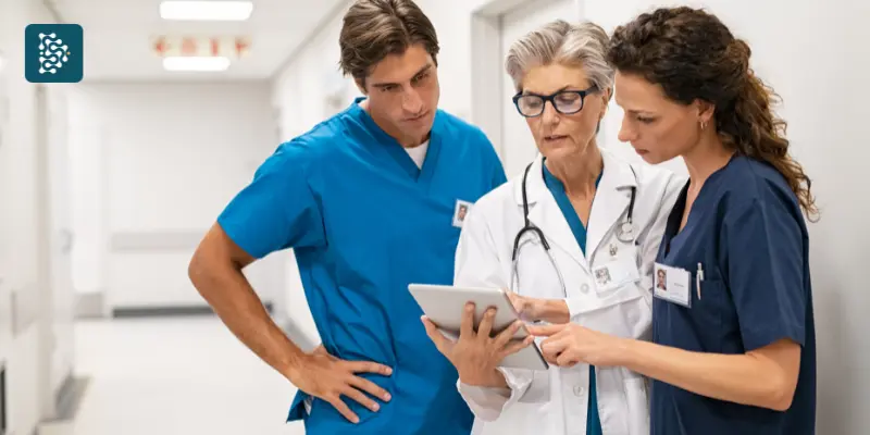 médica sênior ao lado de enfermeiro e técnica de enfermagem vendo informações em um prontuário eletrônico no tablet