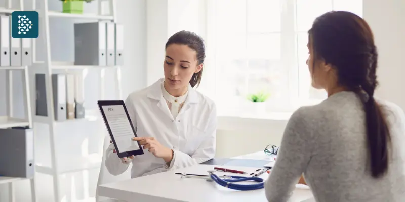 médica usando prontuário eletrônico em tablet para mostrar histórico de consulta de uma paciente