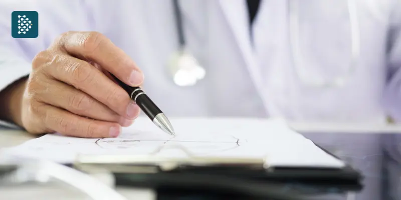 médico anotando em uma prancheta informações sobre glosa médica