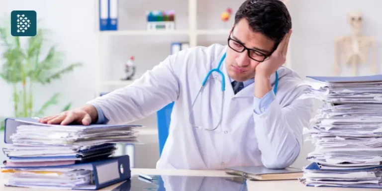 Médico frustrado diante de pilhas de papéis de consultório, simbolizando a falta de organização na clínica e a necessidade de gestão eficiente com o sistema hospitalar Datasigh.