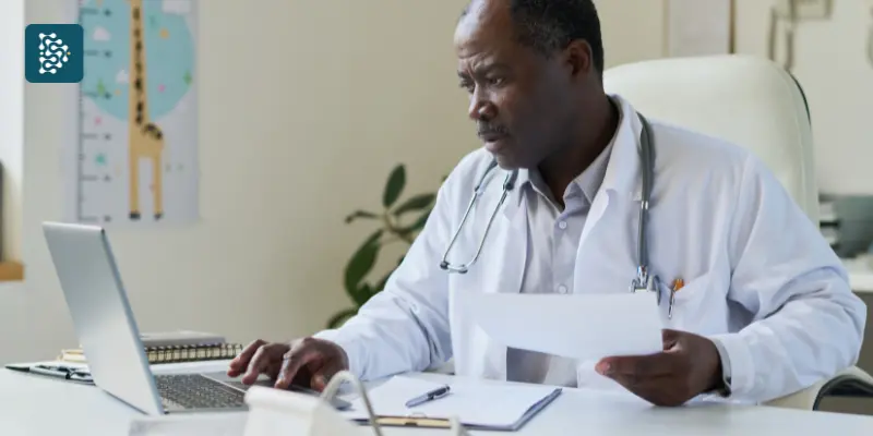 Médico negro analisando planilhas de gestão clínica e administração de consultório, representando o uso do sistema datasigh
