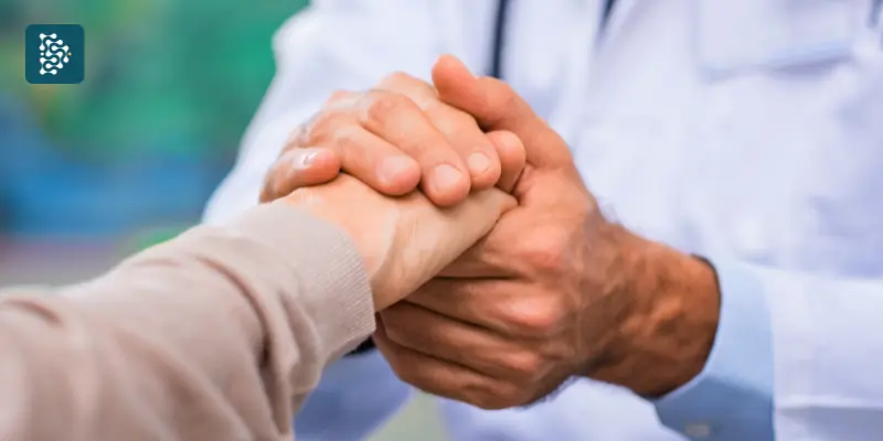 médico segurando a mão de uma paciente