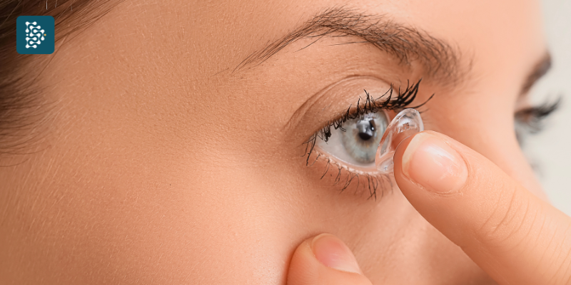 mulher com olhos azuis colocando lente de contato