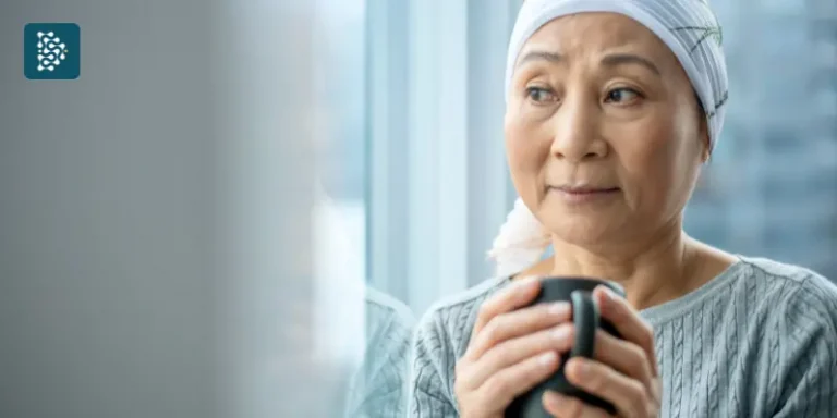 mulher paciente com câncer segurando uma xícara de chá quente olhando pela janela de um hospital que usa o sistema de gestão datasigh