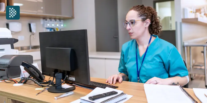 Recepção de hospital com recepcionista mulher em mesa com computador organizando relatórios.