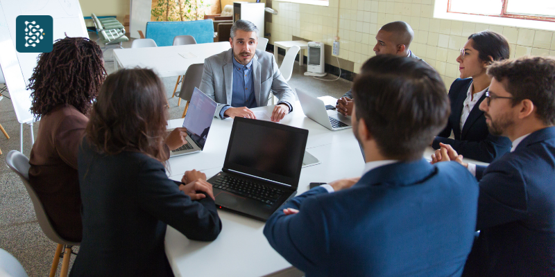 Reunião de equipe com computador na mesa, consultor empresarial orientando estratégias de alta performance com tecnologia em saúde e sistema de gestão hospitalar Datasigh.