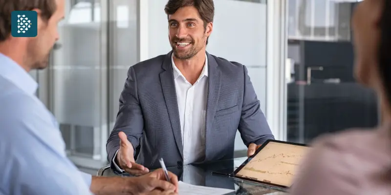 Gestores em reunião analisando gráficos financeiros, com homem jovem de terno cinza, simbolizando o controle financeiro hospitalar com o sistema Datasigh Web.