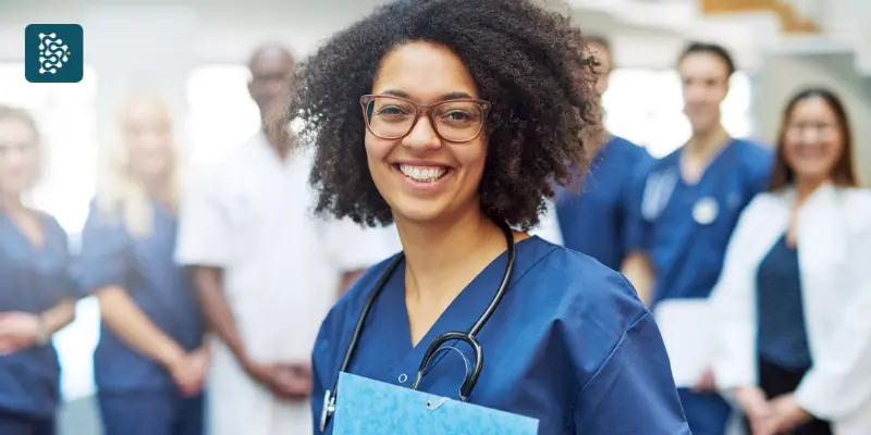 enfermeira negra sorrindo com pasta na mão em treinamento contra Rotatividade em Clínicas Médicas