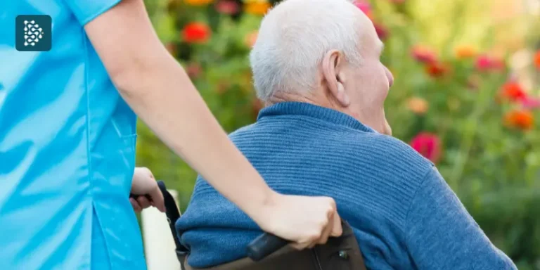 Enfermeira andando com idoso cadeirante no jardim de um