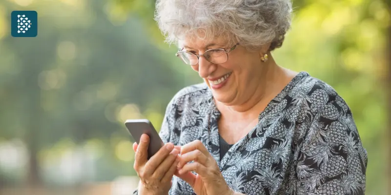 Paciente idosa sênior fazendo marcação de consultas pelo celular com praticidade usando sistema de autoagendamento.