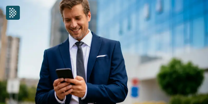 Homem Executivo Gestor de terno fazendo marcação de consultas pelo celular com praticidade usando sistema de autoagendamento.