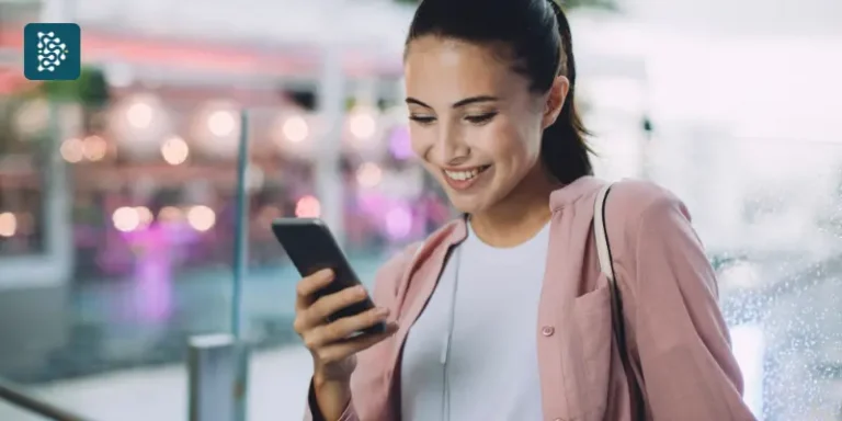 Mulher jovem em um shopping fazendo marcação de consultas pelo celular com praticidade usando sistema de autoagendamento.
